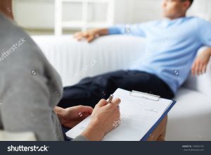 doctor writing notes for patient in the background