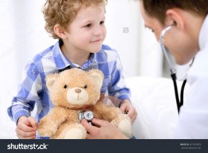 doctor holding stethoscope to child's teddy bear
