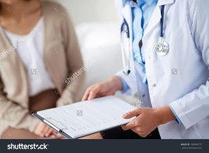 stock-photo-female-doctor-holding-application-form-while-consulting-patient