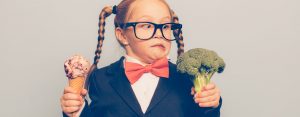 young girl in bowtie holds ice cream and broccoli