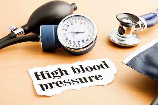 High blood pressure note on a table with a blood pressure cuff and stethoscope.
